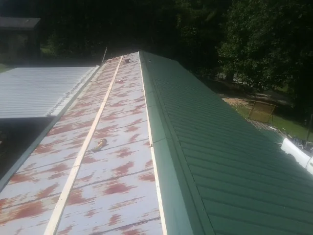 Old rusted panels beside newly installed green metal roofing — Wind Damage Roof Repair by Roofing Brothers in Fontanelle