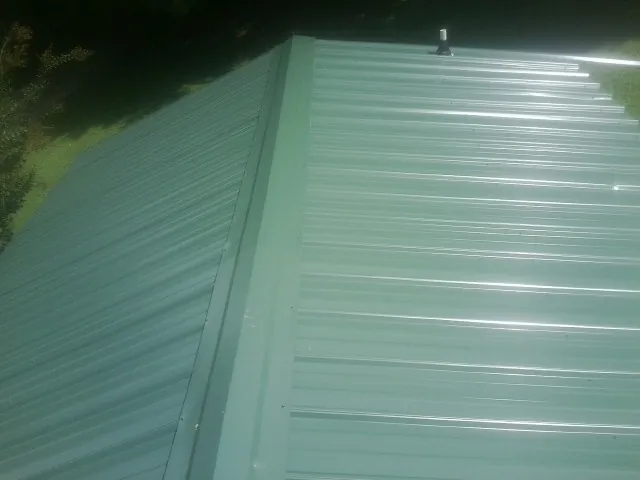 New green metal panels meeting at the ridge of a roof — Flat Roof Repair work by our crew in Fontanelle