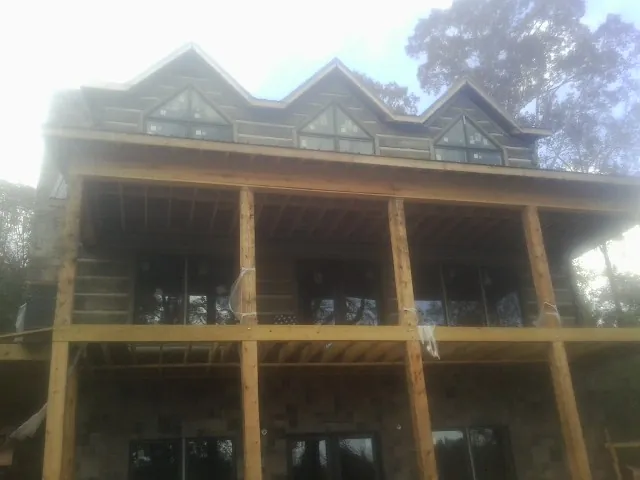 Dormers and porch framing on a large log home under construction — Roof Coating work by our crew in Fontanelle