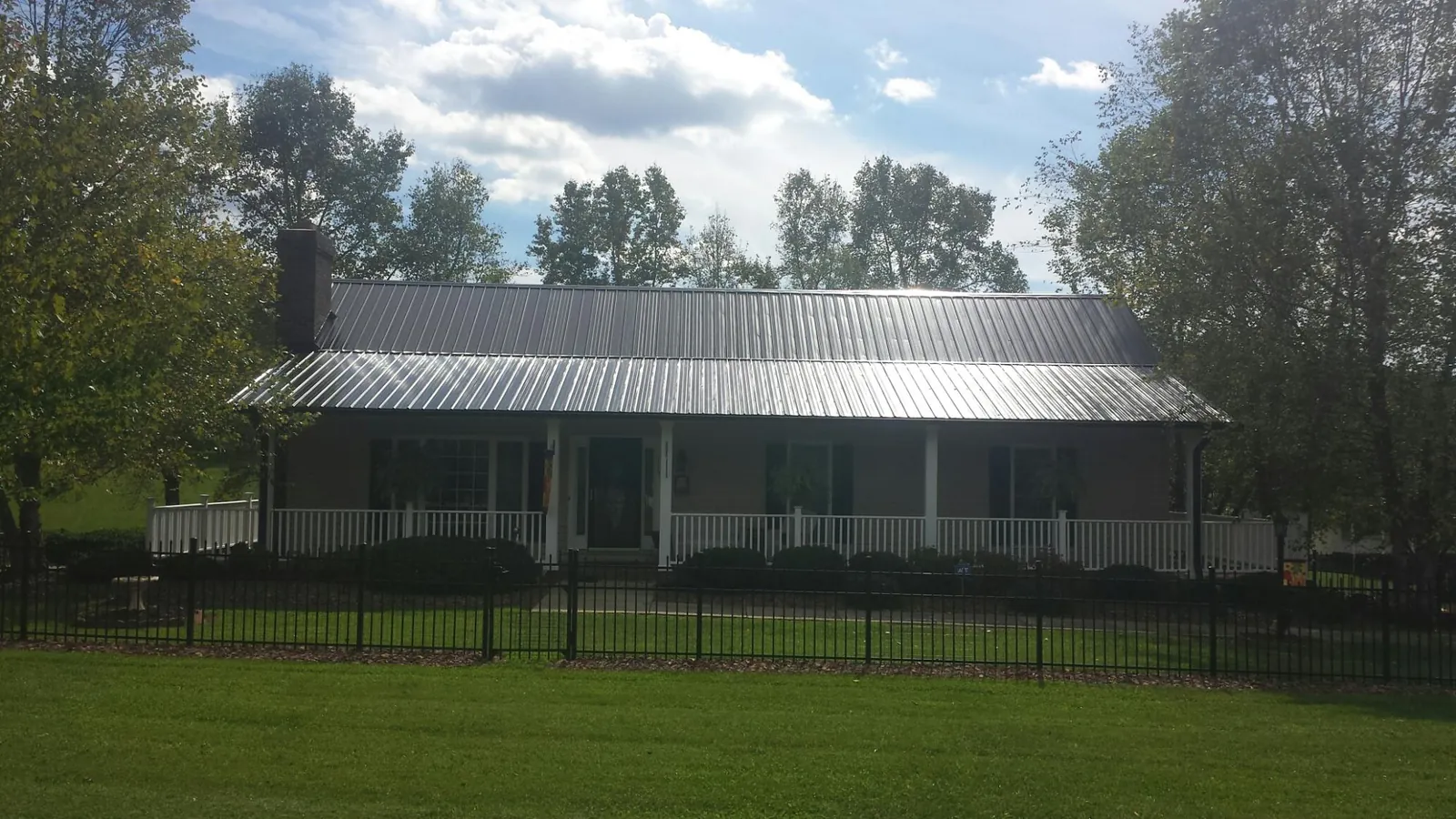 Gray metal roof on a brick ranch with a full width front porch — Gutter Guard Installation work by our crew in Fontanelle