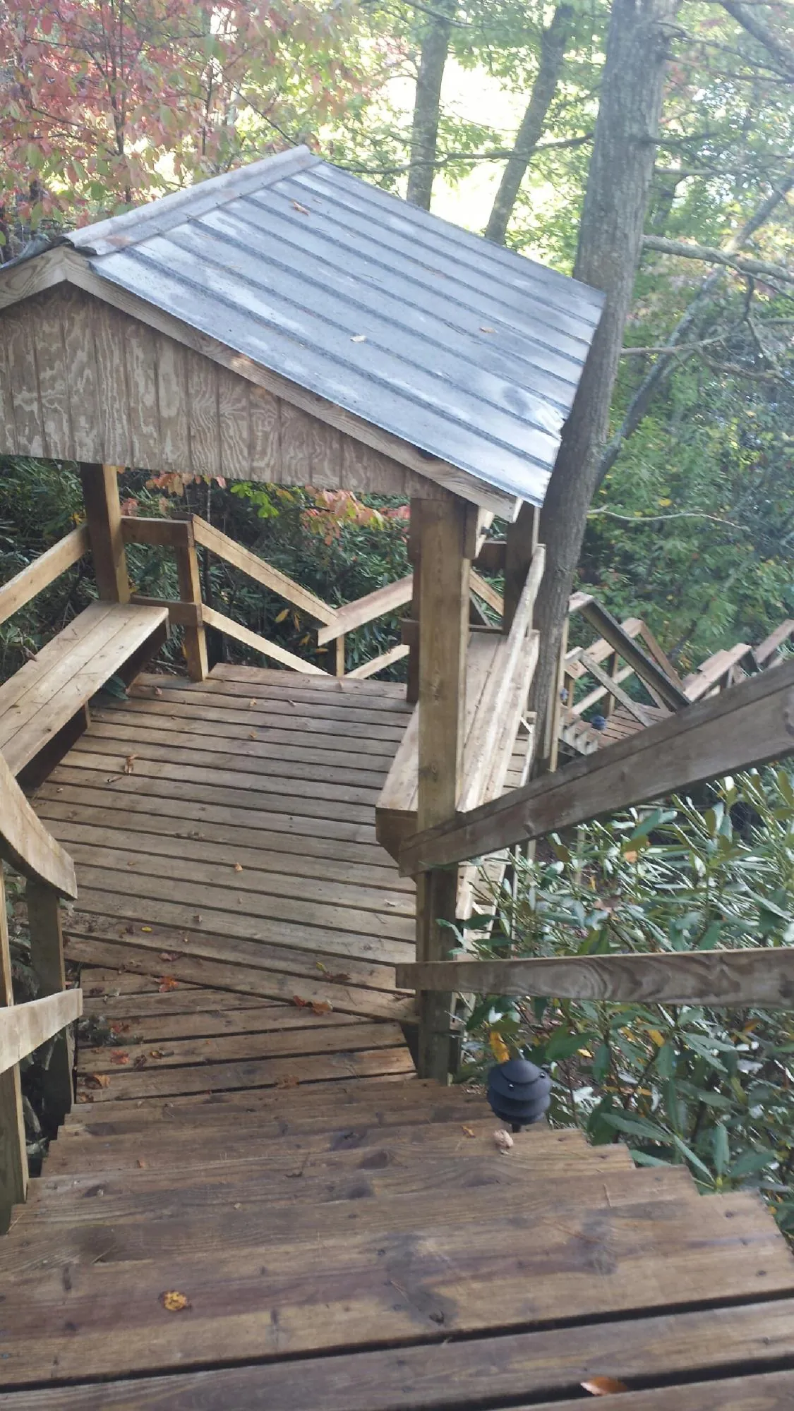 Metal roofed shelter over wooden steps on a wooded walkway — Skylight Repair & Installation work by our crew in Fontanelle