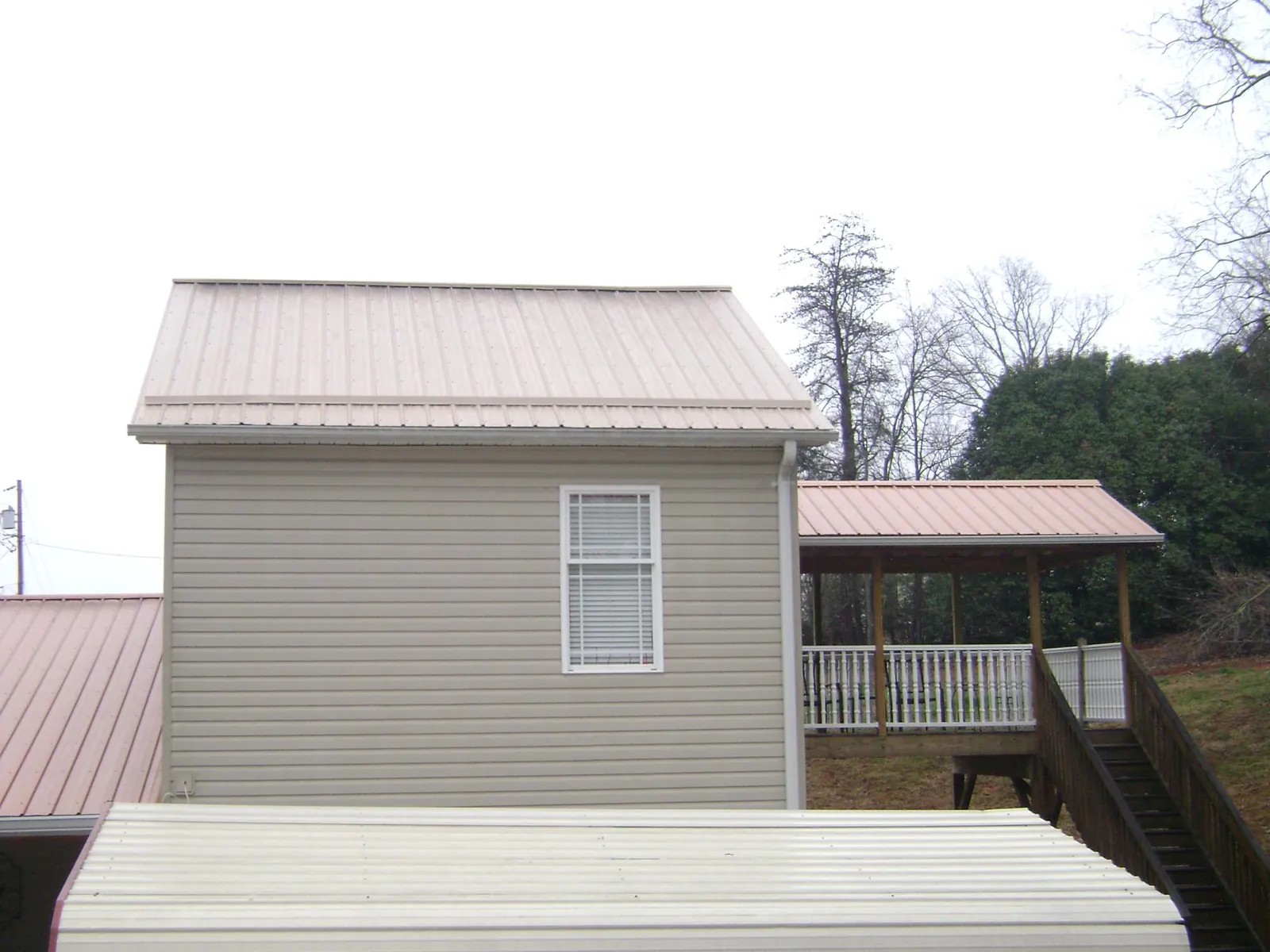 Tan metal roofs on a two story addition and attached porch, from a Roof Replacement job in Fontanelle