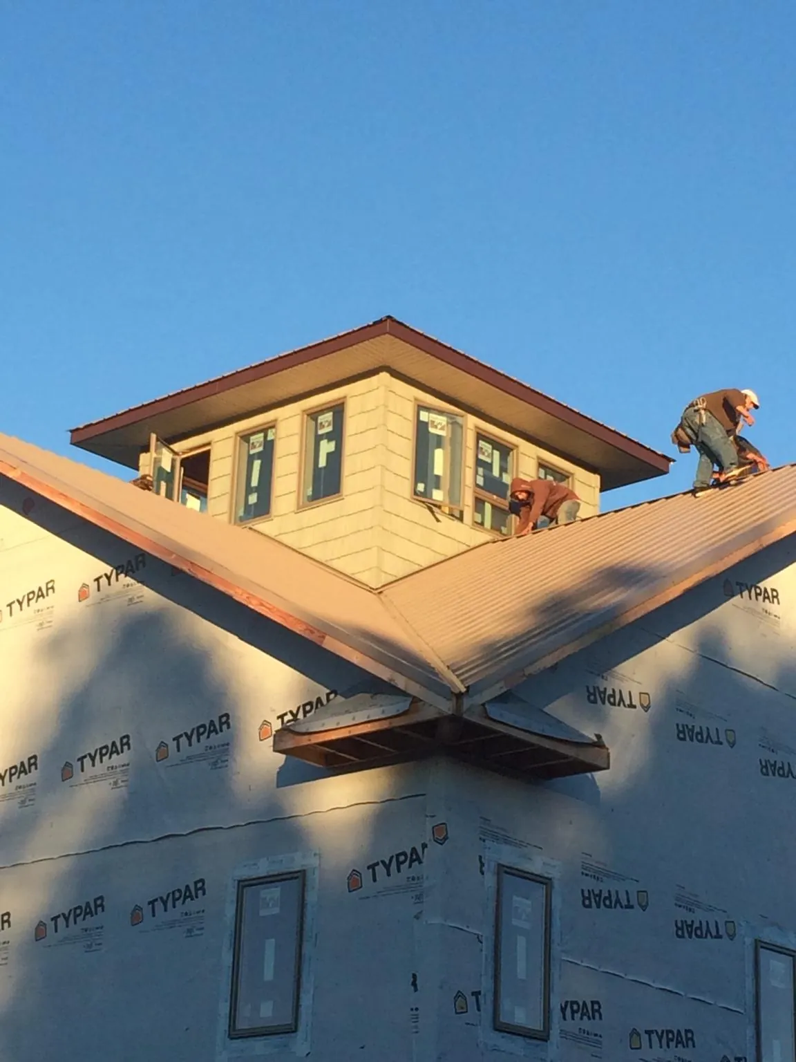 Roofers working around a rooftop cupola on a new metal roof at sunset — Roof Waterproofing in Fontanelle by Roofing Brothers
